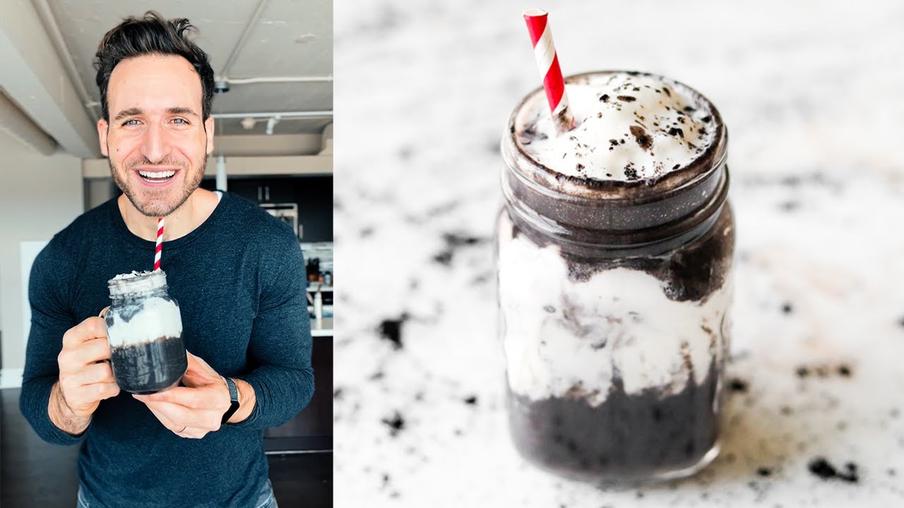 An Oreo flavored protein shake in a glass mug. There's a red and white straw in the mug.