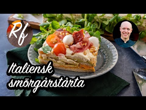 En smörgåstårta med italienska smaker, delikatesser och charkuterier. Fyllningen är i italienska färgerna med grön pesto, röd pesto och vitt bröd. >