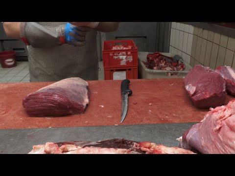 Ein Metzger zeigt wie eine Rinderkeule zerlegt wird