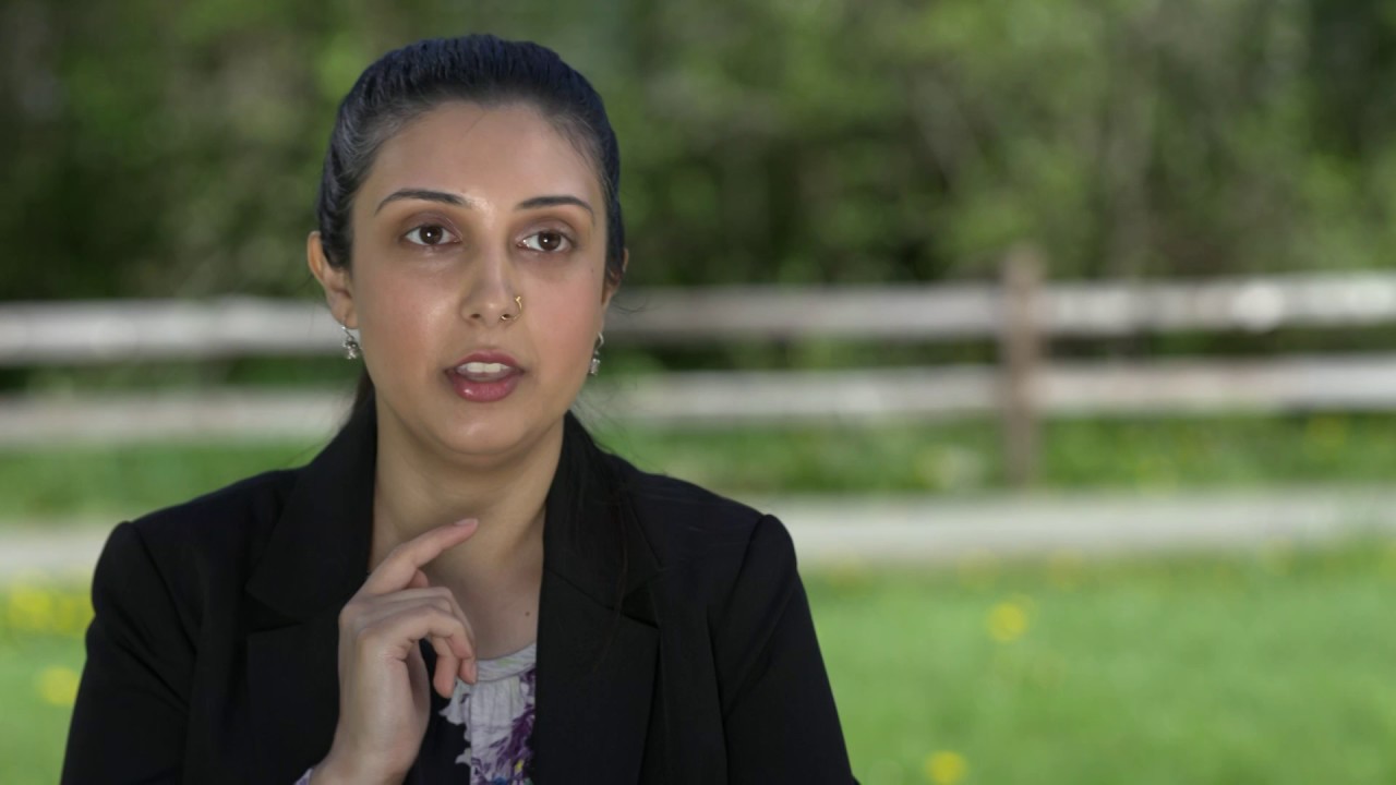 Christina in a black blazer in front of a blurred outdoor backdrop