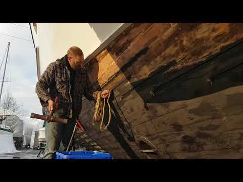 Shipwright caulking wooden yacht