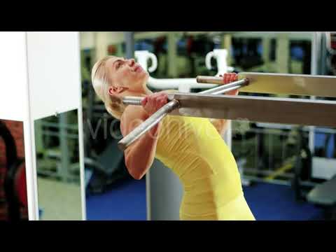 Athletic Woman at the Gym, Girl Performs a Pulling Up Exercise, Exercises on the Horizontal Bar |