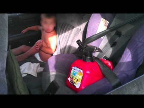 Mom takes child out of car seat to strap in gas can
