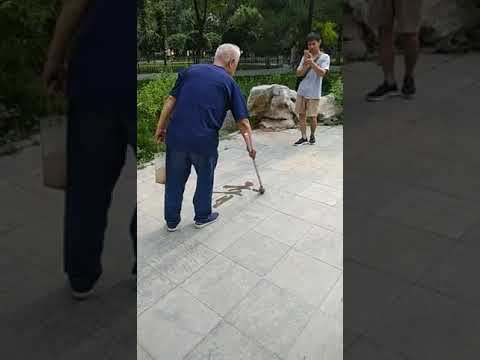 Old man casually draws beautiful water calligraphy on the sidewalk.