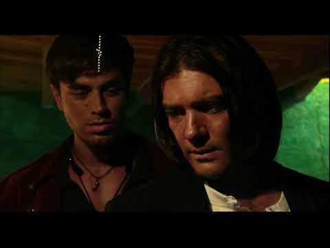 Once Upon a Time in Mexico (2003) trailer still — El Mariachi framed against a sunlit plaza with guitar case and gunsmoke
