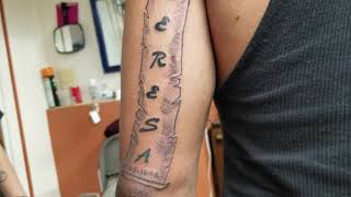 Name in scroll on left male arm tattoo by Boris Kuryakin, July 16, 2018.