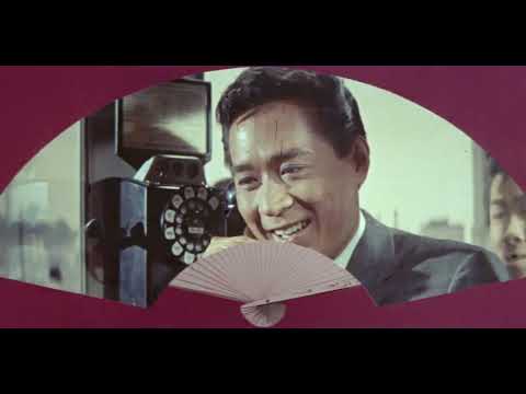 Flower Drum Song (1961) trailer frame with Nancy Kwan and James Shigeta in vibrant Chinatown set