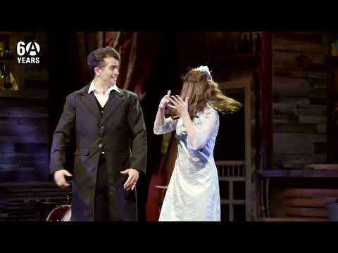 Trailer frame of the finale with the ensemble clapping in tempo under festival lights