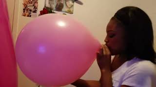 girl blowing up pink balloon