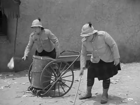 Laurel and Hardy. The boys dancing to a band while picking up litter in Bonnie Scotland