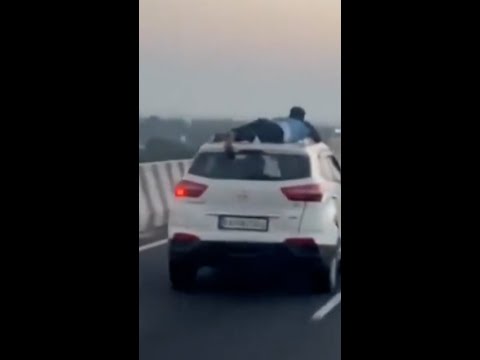 Police officer clings to car during chase in India