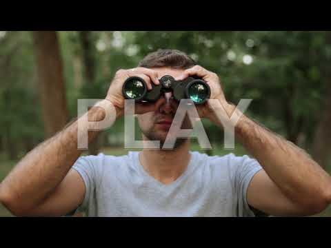 A man with binoculars in the woods.