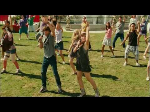 Trailer still — Julia at the piano in a rehearsal hall, lights low, strings starting to swell