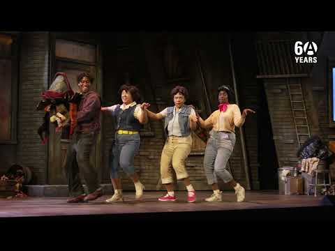 Little Shop of Horrors stage trailer still with Audrey II looming and the Skid Row trio under neon light