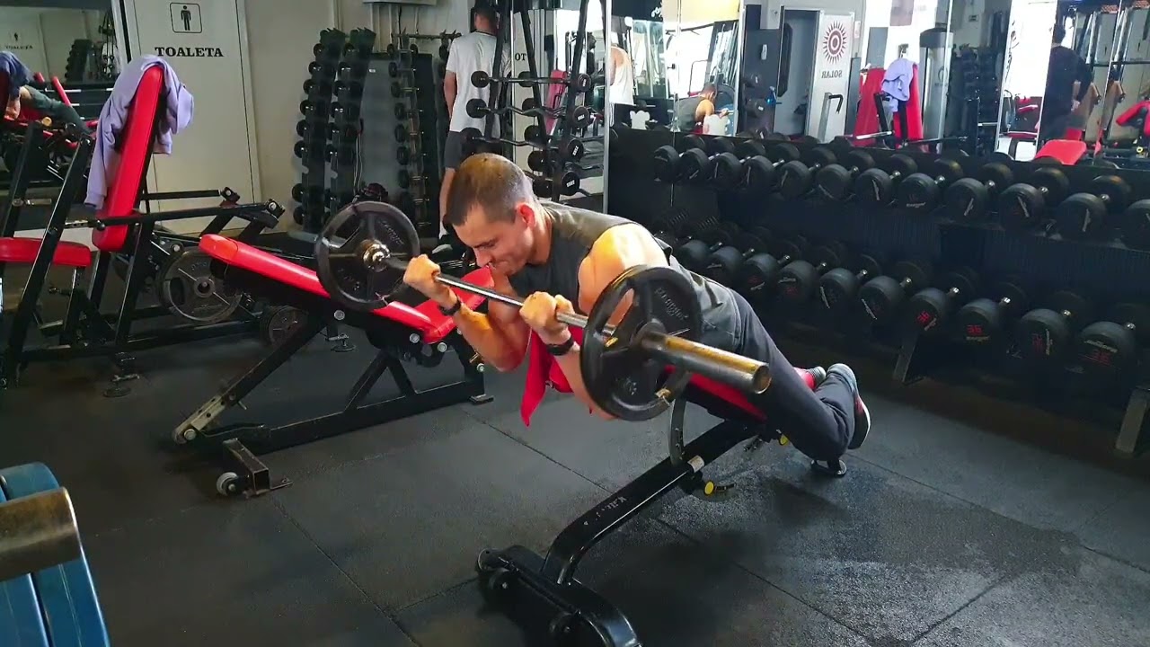 Flexii tip păianjen pentru biceps, din culcat înainte pe o bancă înclinată, cu bara