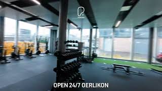 PureGym Zürich Oerlikon: Weitwinkelansicht des Freihantelbereichs mit Bänken, Kurzhanteln und Squat Racks.