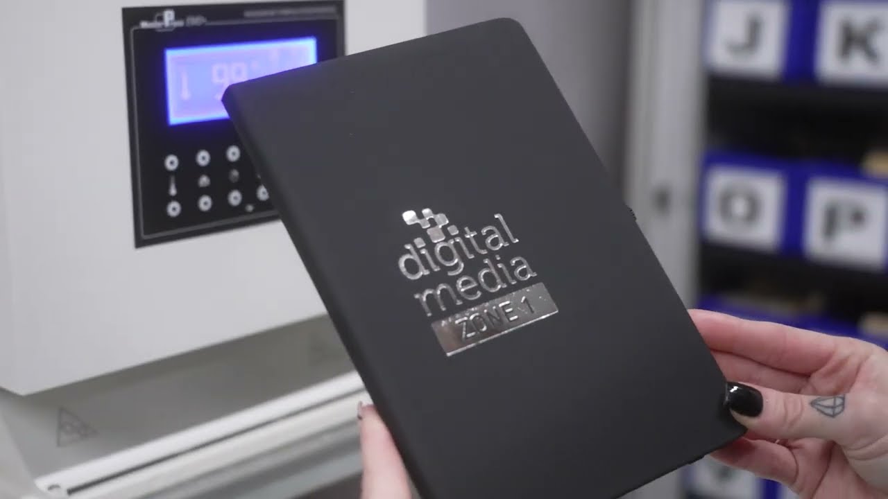 Foil blocking on branded merchandise — metallic foil heat-stamped onto notebooks and packaging using a custom die for a luxury shimmering finish