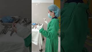 PUTTING ON THE GLOVES BY THE SCRUB NURSE INSIDE THE OPERATING ROOM