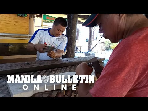 Craftsmen engrave okir design on a Maranao traditional house 'Torogan'