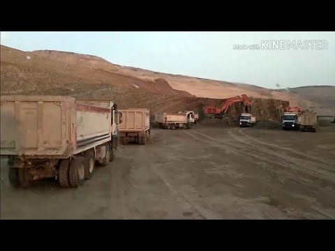 night shift starts with evening sun and rain - excavator loading truck