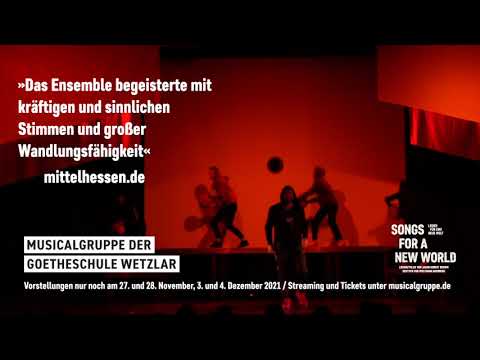 Songs for a New World trailer frame: four singers on a bare stage under concert lighting