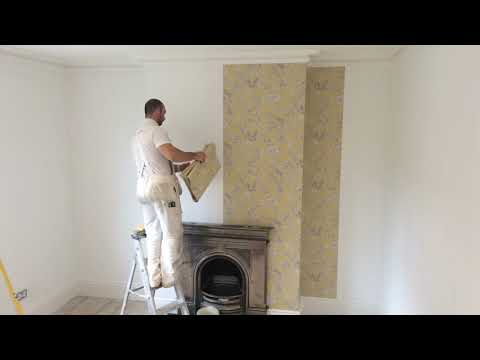 Wallpapering a whole room starting with the chimney breast wall.