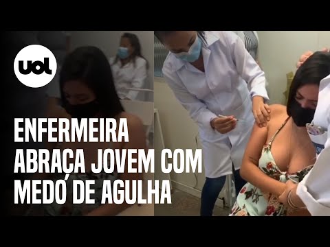 Enfermeira abraça jovem com medo de agulha durante vacinação contra covid