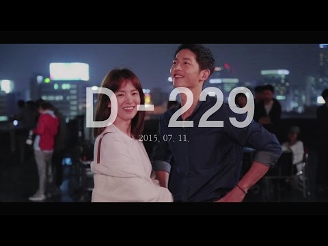 The two leads of Descendants of the Sun on set at night against a city skyline, with a countdown caption reading D-229, 2015.07.11