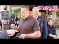 Arnold Schwarzenegger Smokes A Cigar While Signing Autographs For Fans While Leaving His Hotel In NY