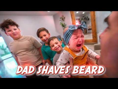 Crying baby in orange overalls held by an adult, while three older siblings gaze on; bold red text at the bottom reads 'DAD SHAVES BEARD'.