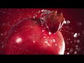 Super slow motion water drips on rotating pomegranate . On a black background.