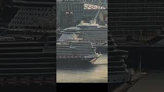Helicopter buzzes large cruise ship as another cruiser reverses from dock