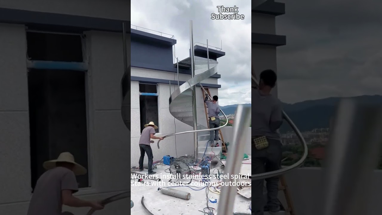 Workers installing stainless steel spiral staircase outdoors