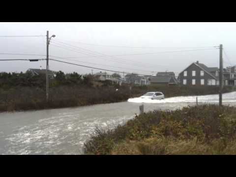 A car drives on a flooded Menauhant Road, Falmouth