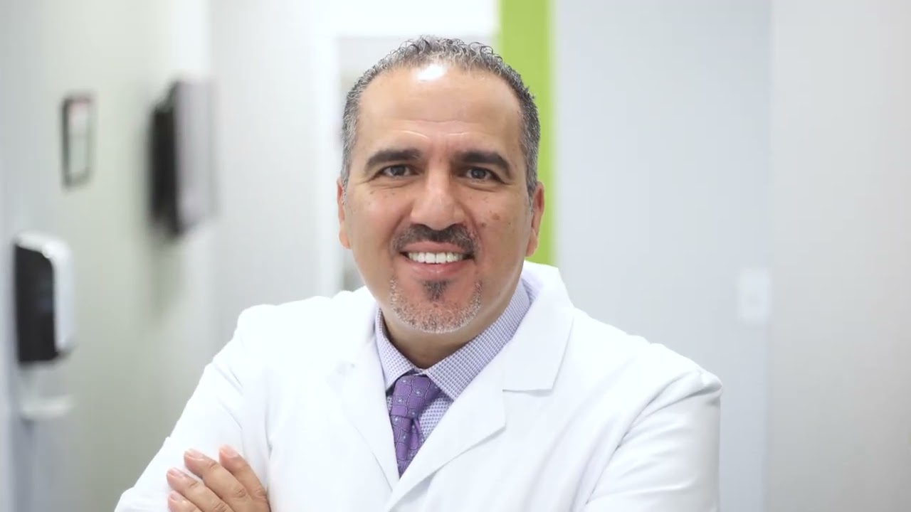 Doctor Sam Alkhoury smiling in a white lab coat