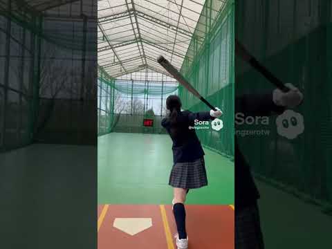 日本の女子高生がバッティングセンターで野球を打ち、カキーンと快音を響かせる。
