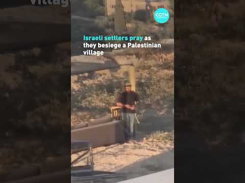 Israeli settlers pray as they besiege a Palestinian village