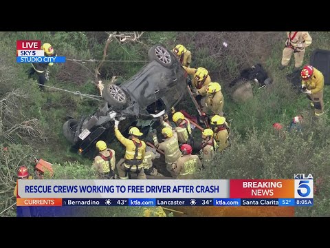 Rescue crews work to free driver after crash off Mulholland Drive