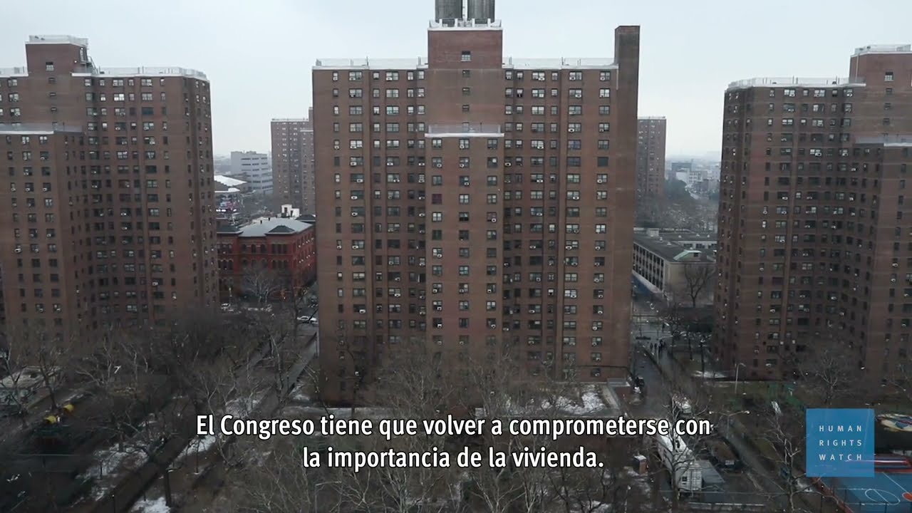 Woman standing on balcony looking at public housing buildings.