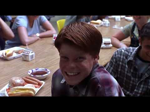 Official trailer frame: David Spade as Joe Dirt, mullet and denim foregrounded, setting up the film’s classic-rock tone