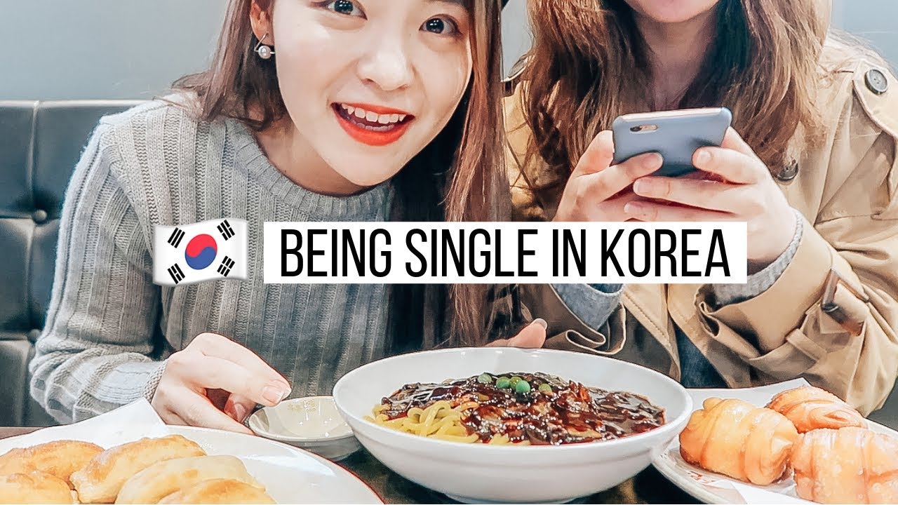 A vlogger sitting alone at a Korean restaurant on Black Day eating a large bowl of jajangmyeon noodles with chopsticks while wearing all black clothing