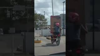 mulher leva televisão na garupa de moto, cai na saída de shopping em João Pessoa, A mulher ainda tenta segurar a caixa com a televisão, mas com o impacto da batida e o peso do aparelho ela fica pendurada de cabeça para baixo