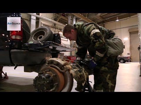 Airmen working on vehicles while wearing MOPP (Mission Oriented Protective Posture) gear