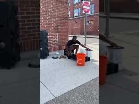 A drummer plays on pots, pans and buckets on the side of the street
