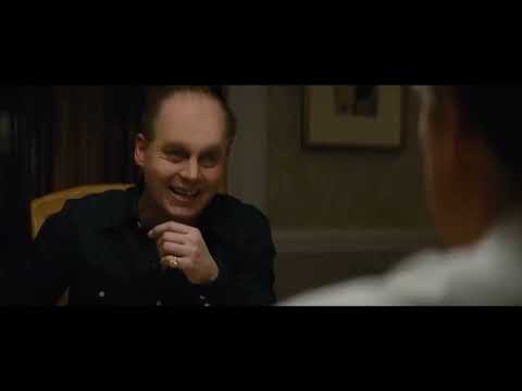 Over-the-shoulder trailer shot of an FBI briefing room where the score’s strings tighten the air