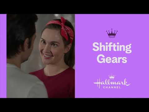 Hallmark’s Shifting Gears trailer still: Jess and Luke framed by neon garage lights and classic cars