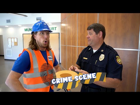 Construction worker in an orange safety vest and blue helmet talks with a police officer in a courthouse lobby; a 'CRIME SCENE' overlay is across the image.