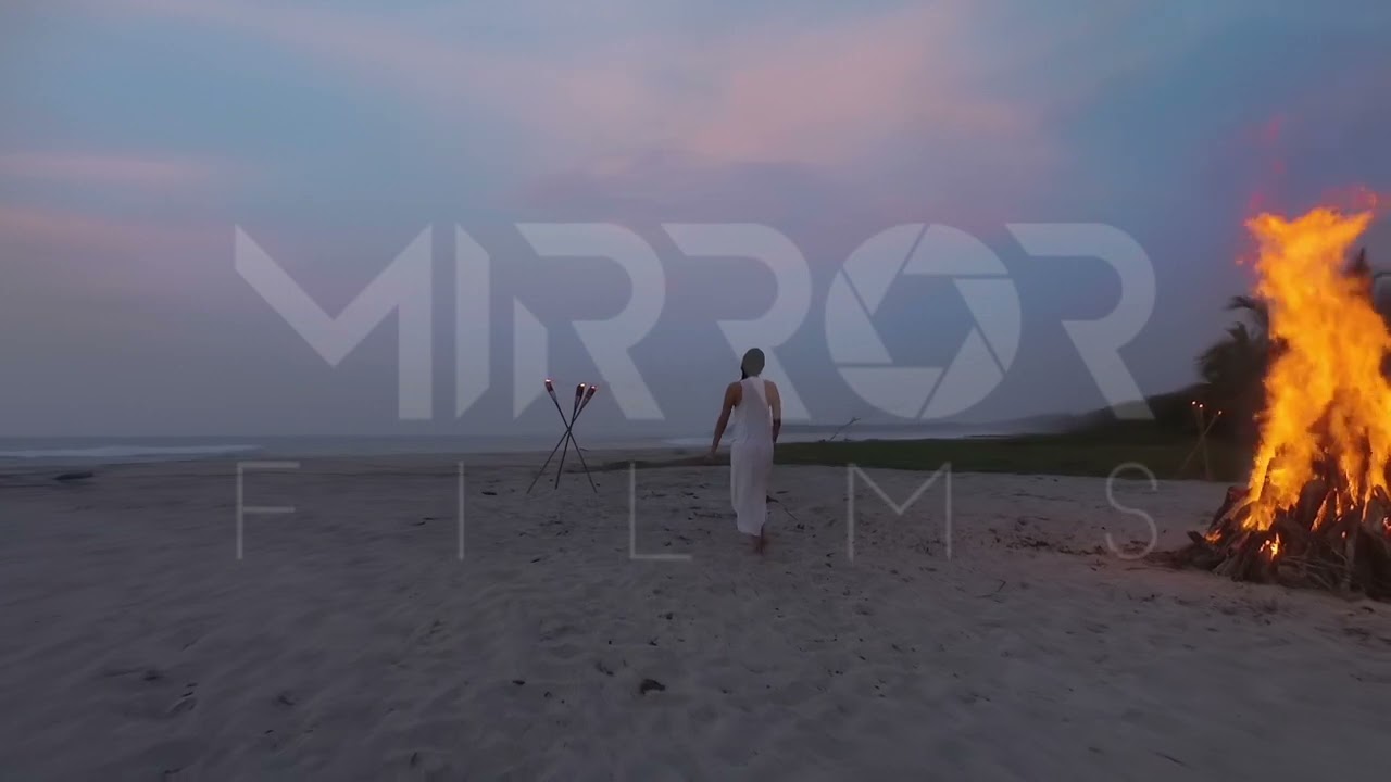 Mujer bailando en playa con fogata