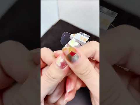 Sticker aligns over glossy thumbnail—floral overlay meets geometric shimmer in quiet precision