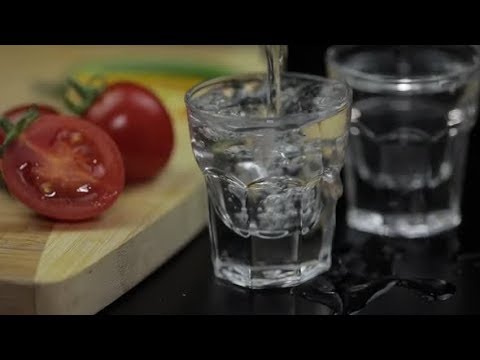 Pour Alcohol Drink Vodka From a Bottle in Shot Glass. Surface with Snacks | Stock Footage -